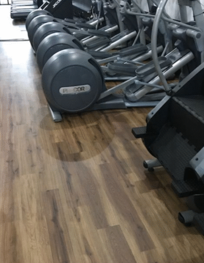 Durable Luxury Vinyl Tile (LVT) flooring in a fitness facility, featuring seamless transitions between exercise equipment and entry spaces, designed for high-traffic areas.