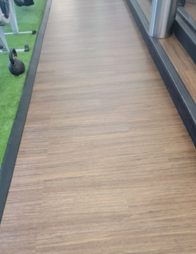 Durable Luxury Vinyl Tile (LVT) flooring in a high-traffic entryway, showcasing seamless transitions to rubber and turf areas, emphasizing functionality and aesthetic appeal.