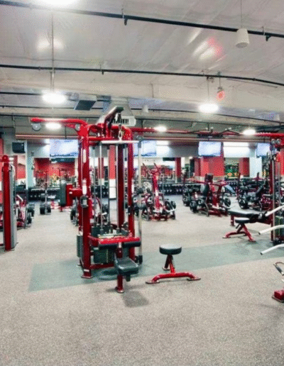 Gym interior showcasing various workout equipment, including weight machines and benches, with rubber flooring designed for safety and performance.