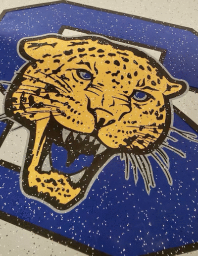 Custom-designed rubber flooring featuring a fierce leopard logo, emphasizing team identity and school pride, in a weight room setting.