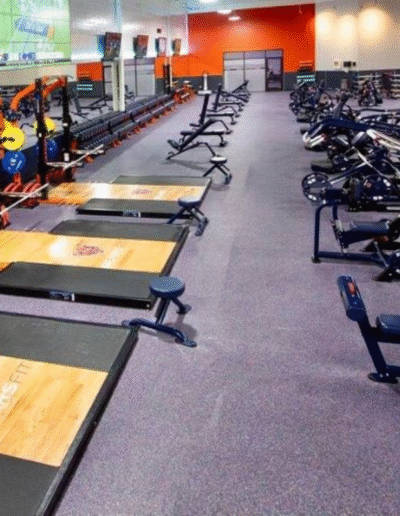 Gym interior showcasing weightlifting area with rubber flooring, benches, and equipment, emphasizing safety and performance for fitness activities.
