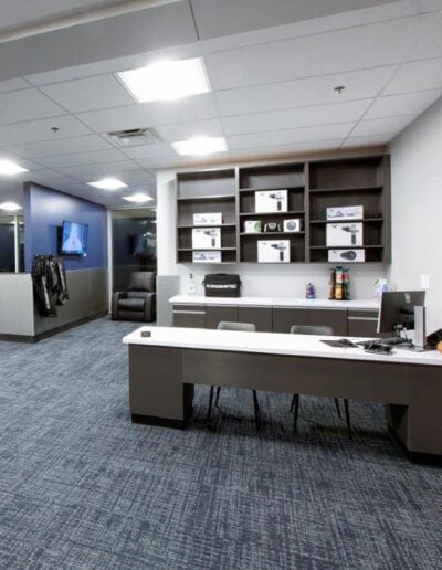 Modern entryway with durable carpet tile flooring, sleek reception desk, and organized shelving displaying equipment, emphasizing functionality and aesthetic appeal for high-traffic areas.