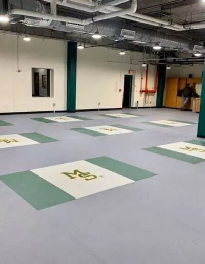 Sports flooring installation featuring custom logo applications in green and white, showcasing brand identity for athletic facilities.