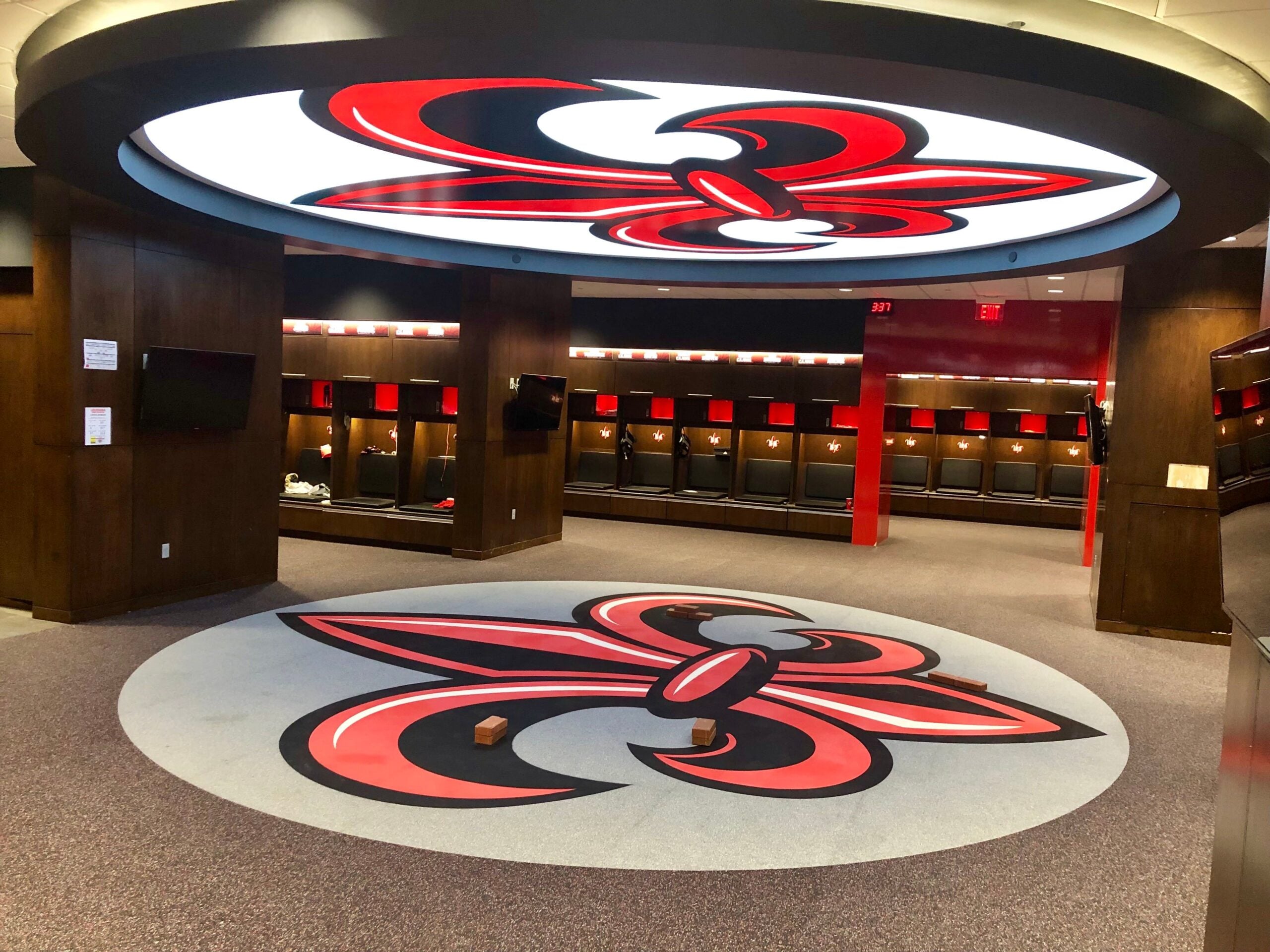 Custom rubber flooring with Louisiana Ragin' Cajuns logo in athletic locker room, showcasing team branding and modern design elements.